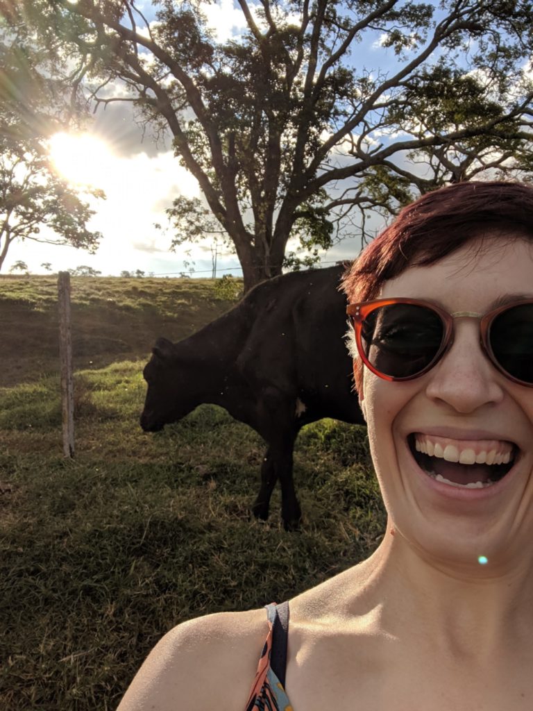 Portrait of Rachel happy to see a cow on a farm in Brazil.