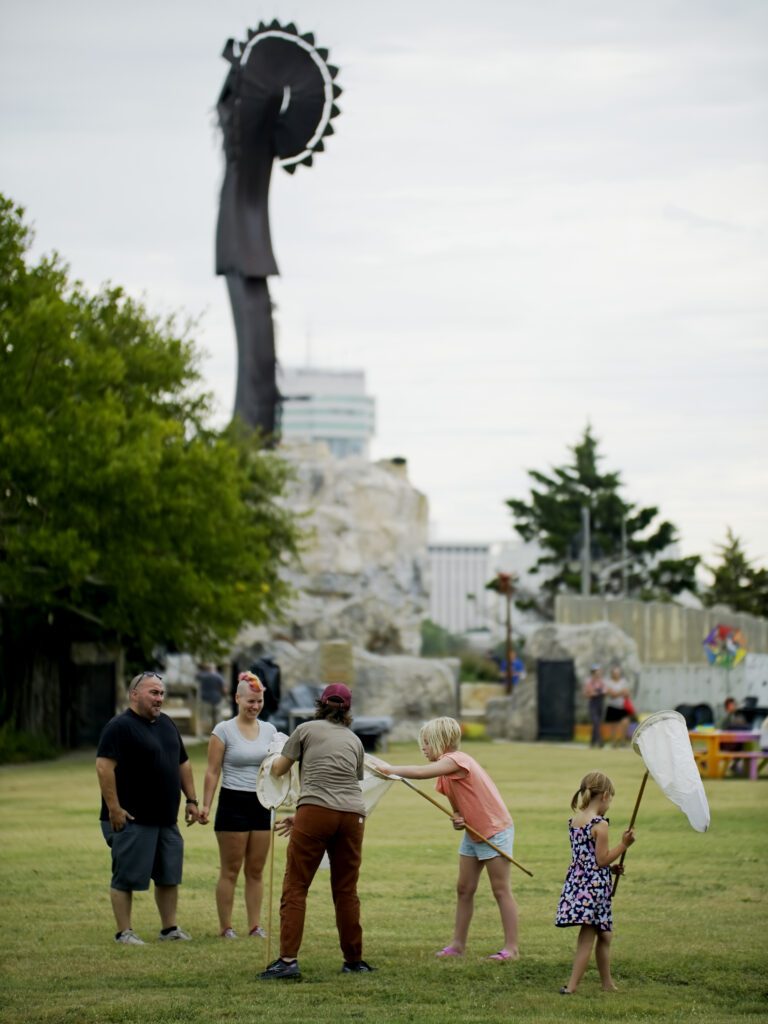 Families and volunteers catch bugs under the keeper of the plains with professional bug nets.