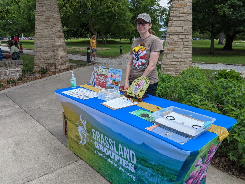 A staff member stands at a colorful table of activities and information.