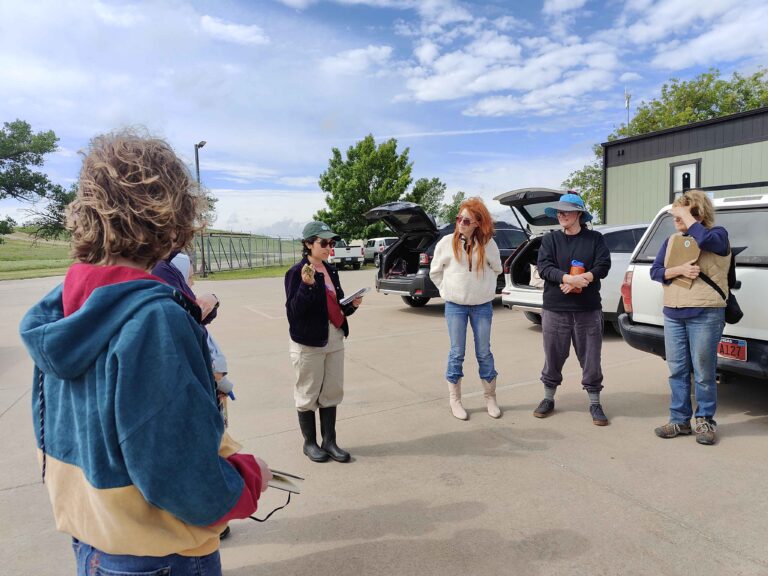 Participants stand in a circle outside, sharing their journals.