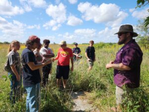 GG’s Grassland Ecology class at Friends University exploring Ninnescah with Dexter Mardis, Field Station Manager. One student holds a ringneck snake while others look on.