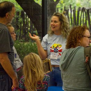 Visitors engage with volunteer Becca inside the museum.
