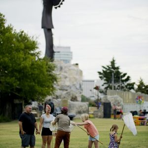 Families and volunteers catch bugs under the keeper of the plains with professional bug nets.